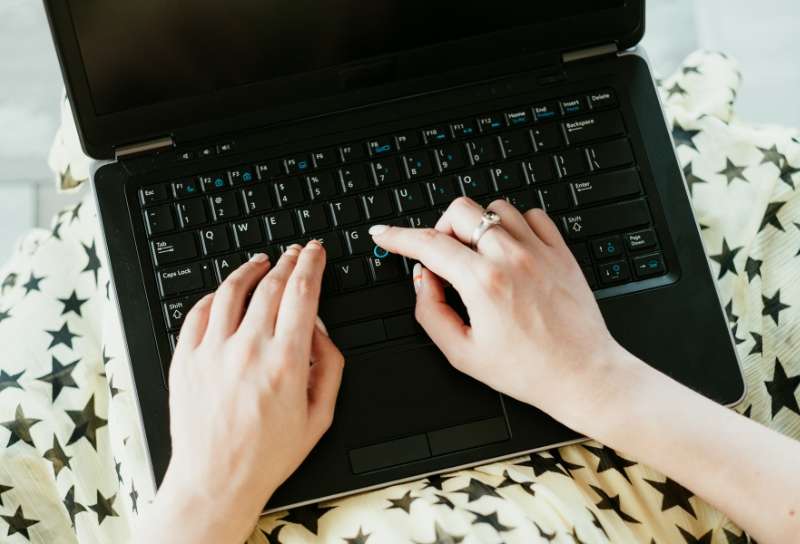Frau schreibt auf einem Laptop an ihrem Exposé.